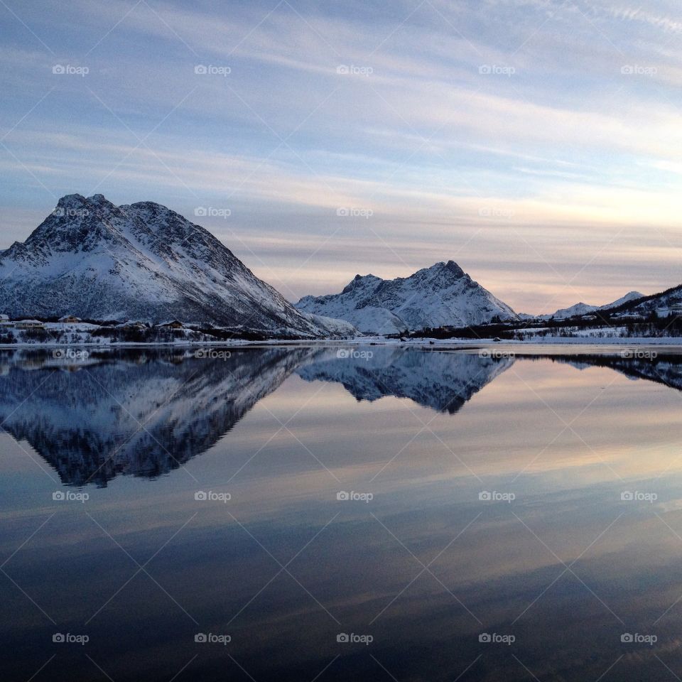 Snowy mountains reflecting in lake