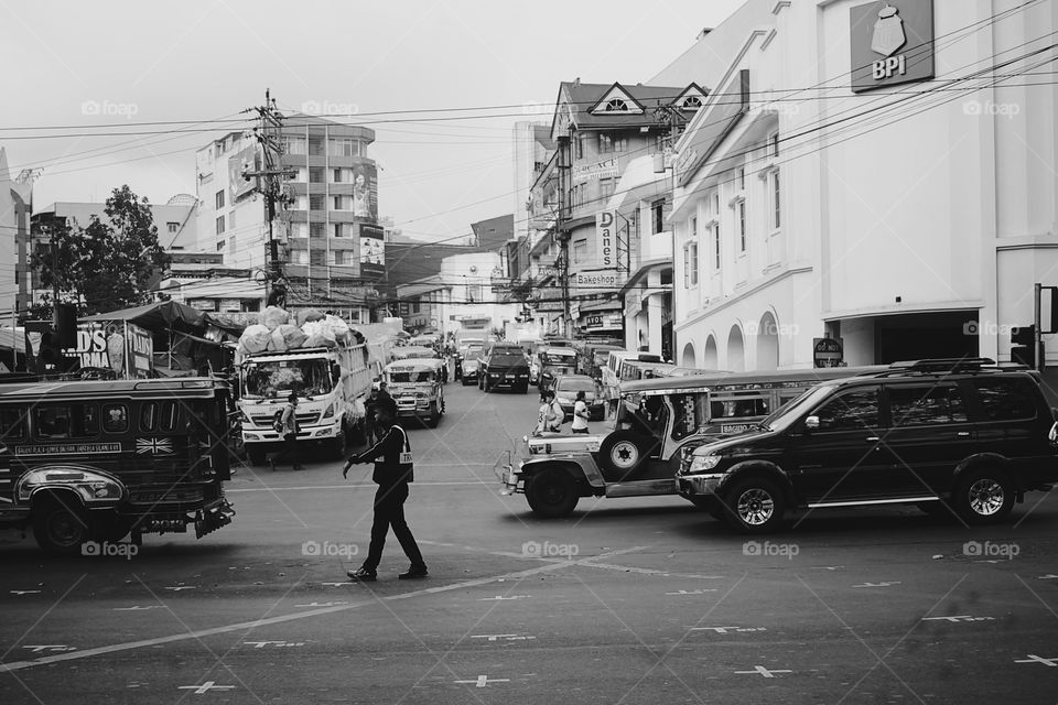 A policeman controlling the traffic in a busy street.