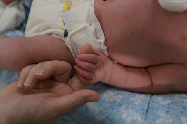 Baby holding a finger in a humidicrib