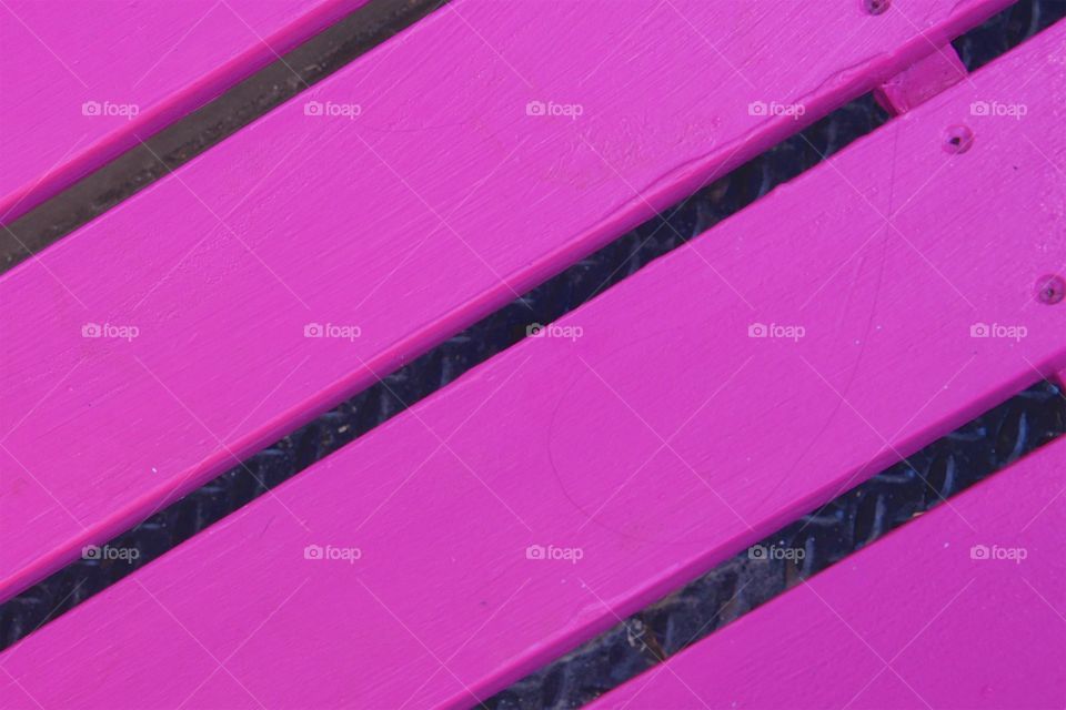 A closeup of a pink wooden bench in 
Manhattan , New York City.