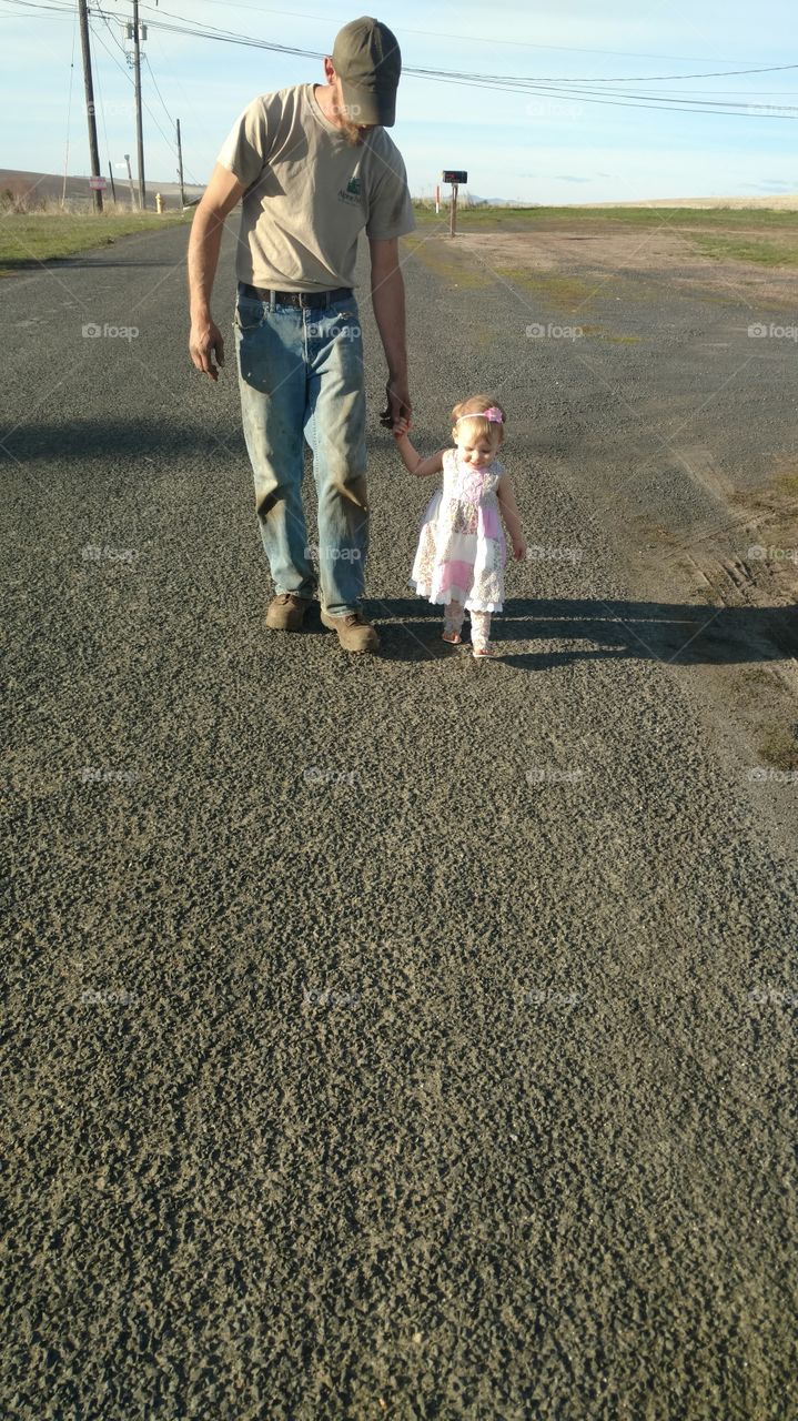 Father and daughter walking on road