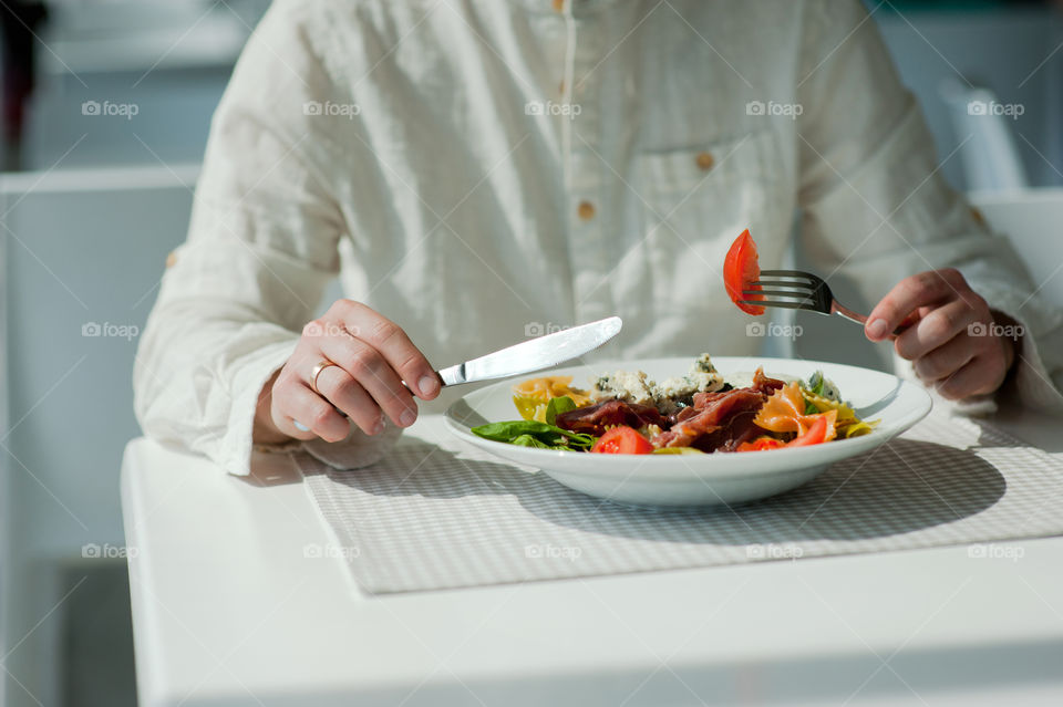 close-up of a young man eating a salad in a light kitchen