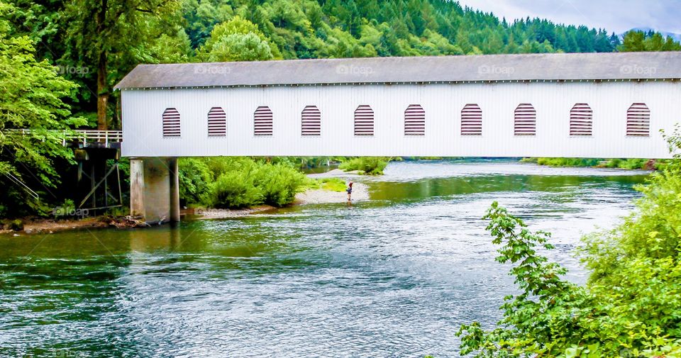 Vintage covered bridge over river. 