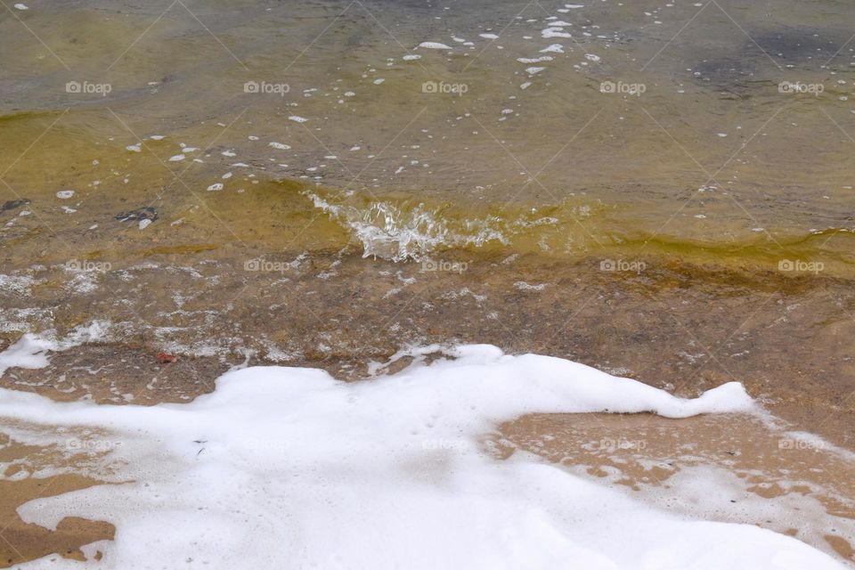 Cold waves throw foam on shore