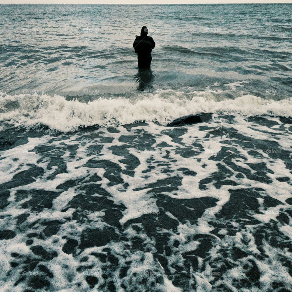 Fisherman with fishing rod in sea