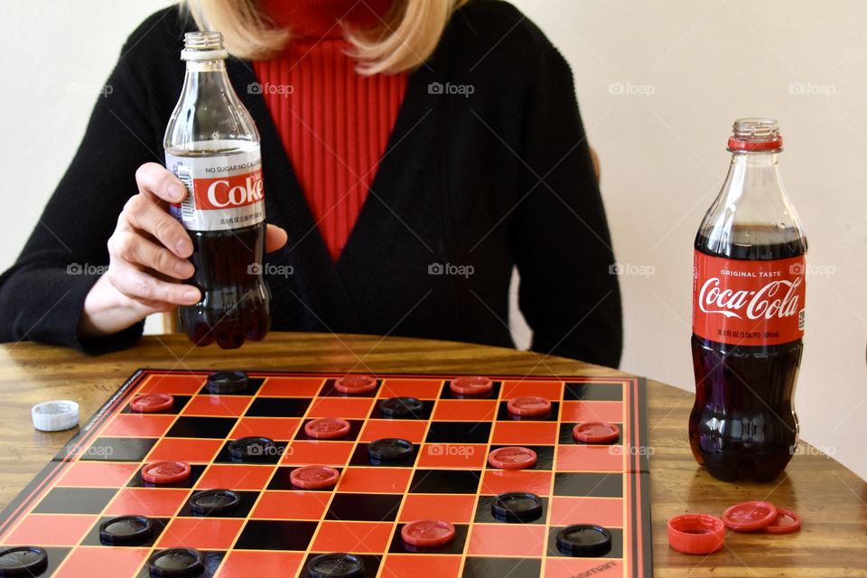 Woman drinking Diet Coke and playing checkers 