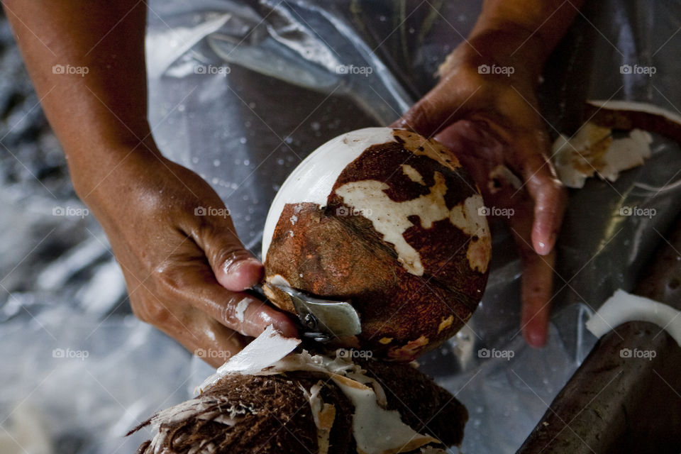 Person cutting coconut in factory