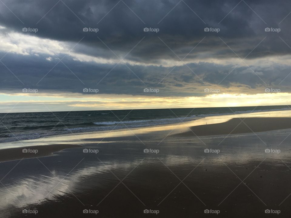 Evening walk on beach with big clouds and little sunshine 