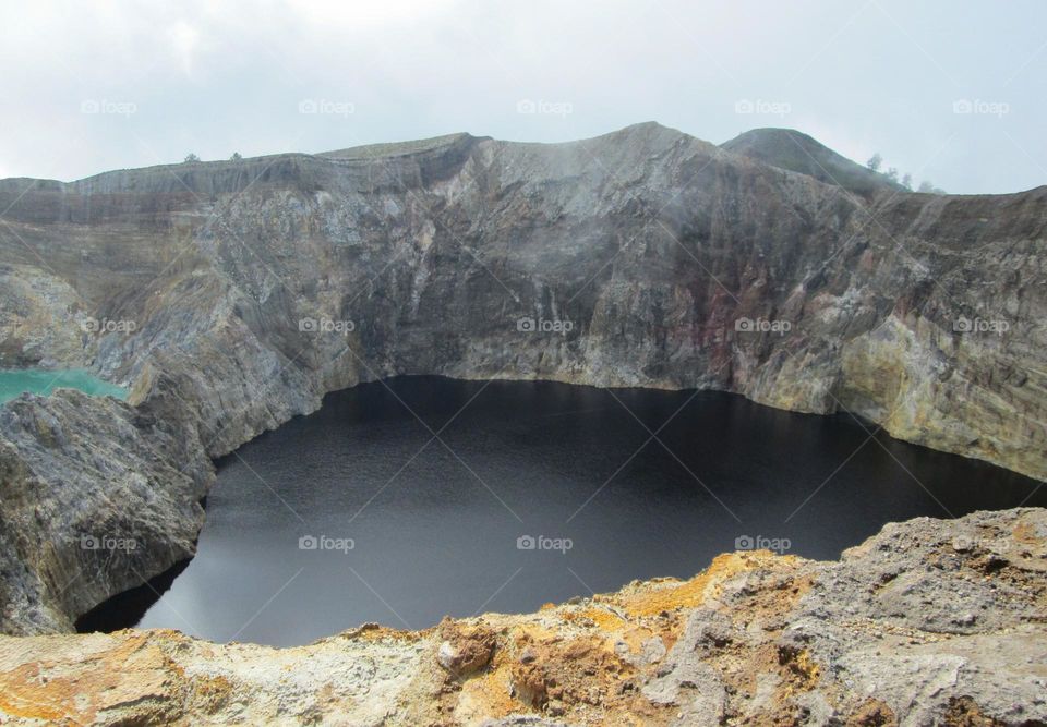 Lake Kelimutu with its black water color. The walls of the lake are naturally formed from mountain rocks.