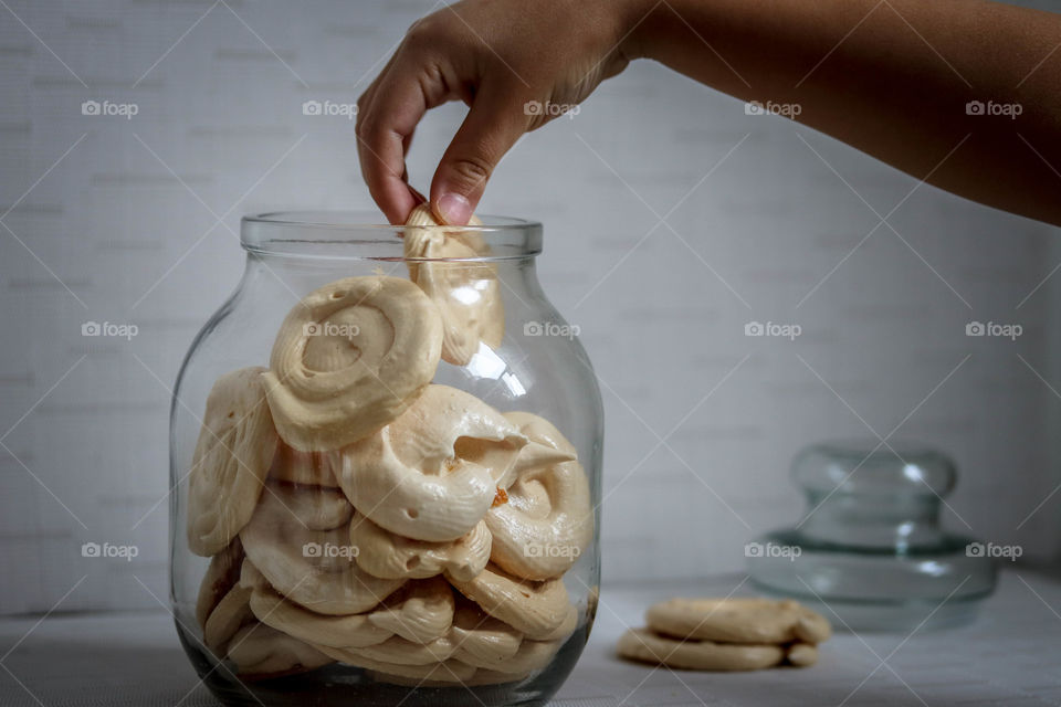 Child's hand is taking meringue from a jar