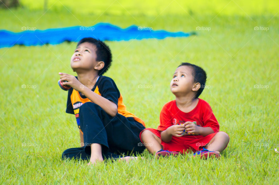 Two boy sitting on park and looking up