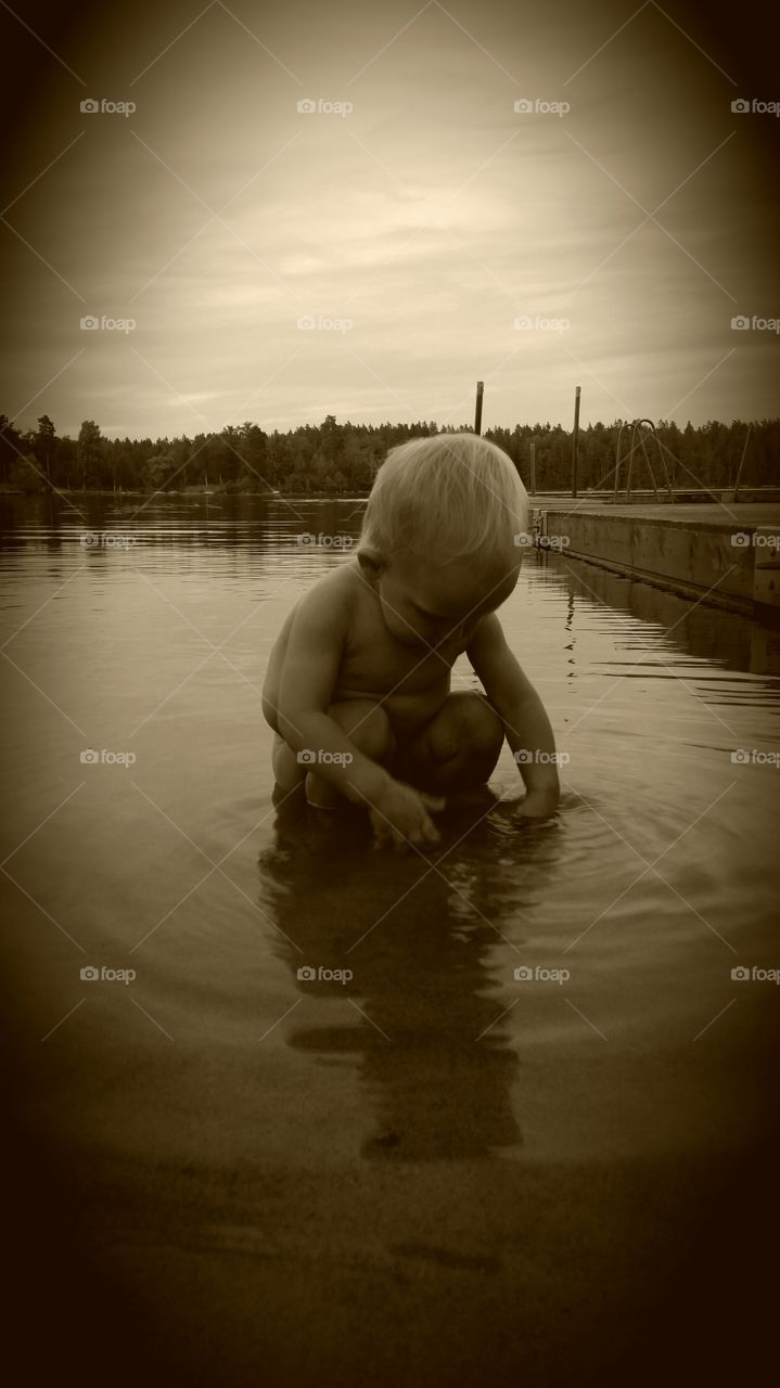 One year old baby bathing in a lake in Sweden