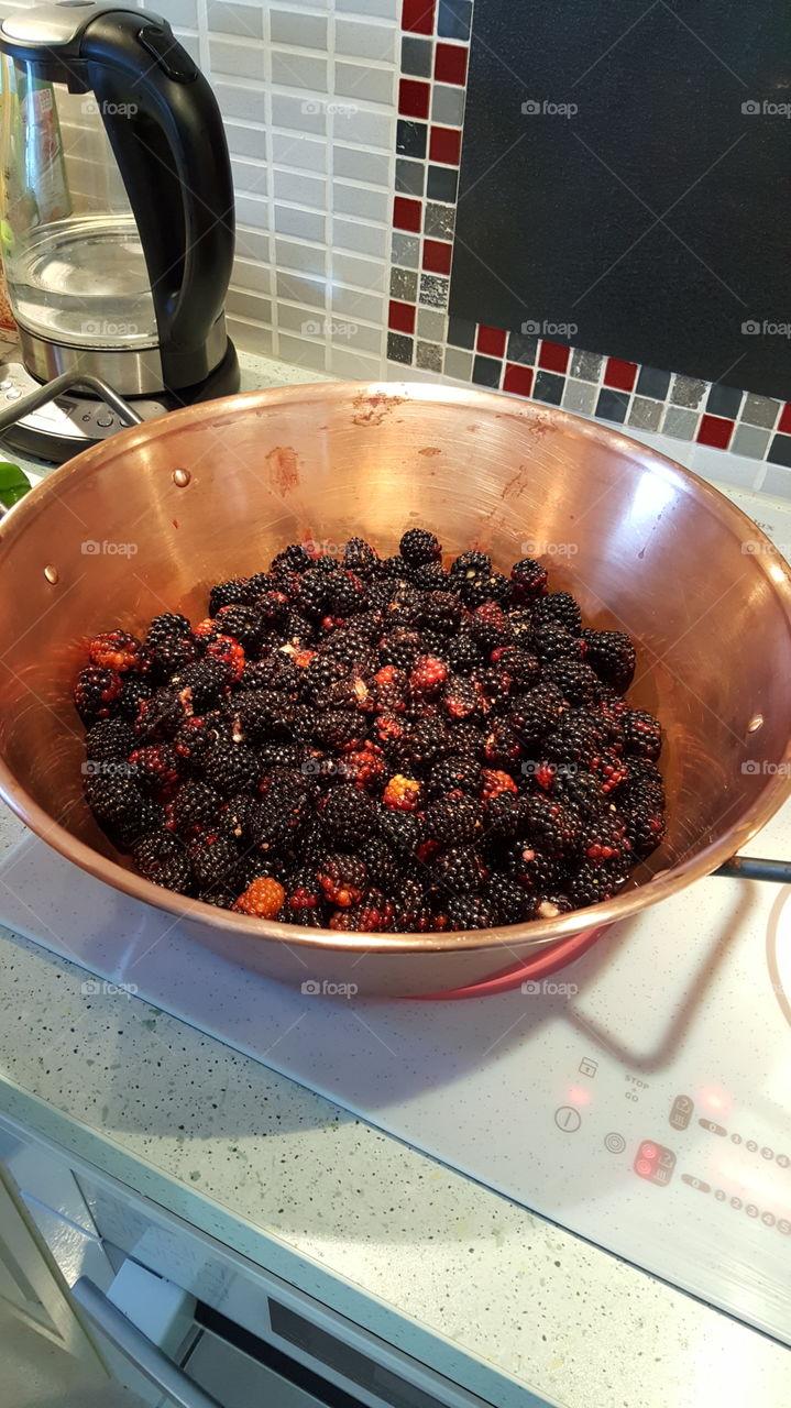 Cooking homemade black berry jam in a traditional copper skillet