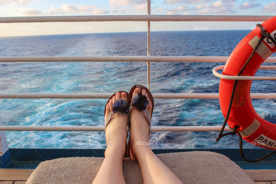 Cruise vacation. Relaxing lying down on deck lounger,  enjoying sunset in turquoise blue ocean background. Summer holidays. Casual lifestyle. Sunbathing. Travel destination.