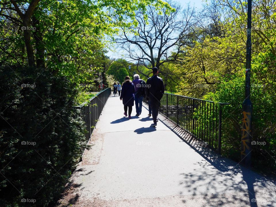 People walking over a narrow bridge in a park