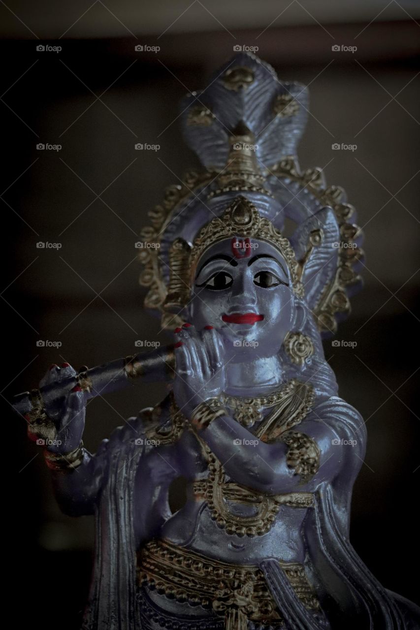 silver colored idol of Lord Krishna