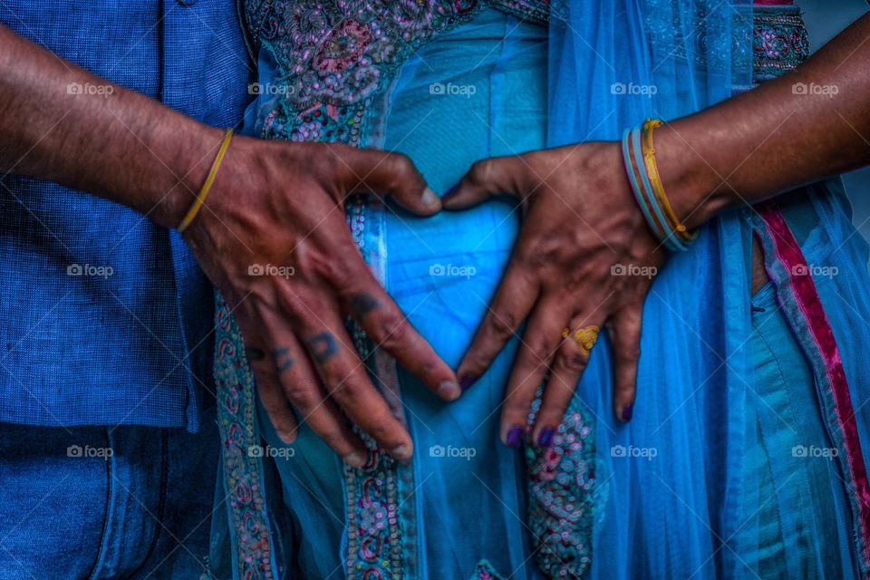 Indian couple showing a heart with their hands infront of the womb.