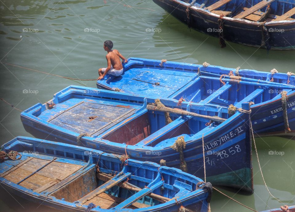 Boy resting on a boat after a swim in the harbour. Essaouira, Morocco.