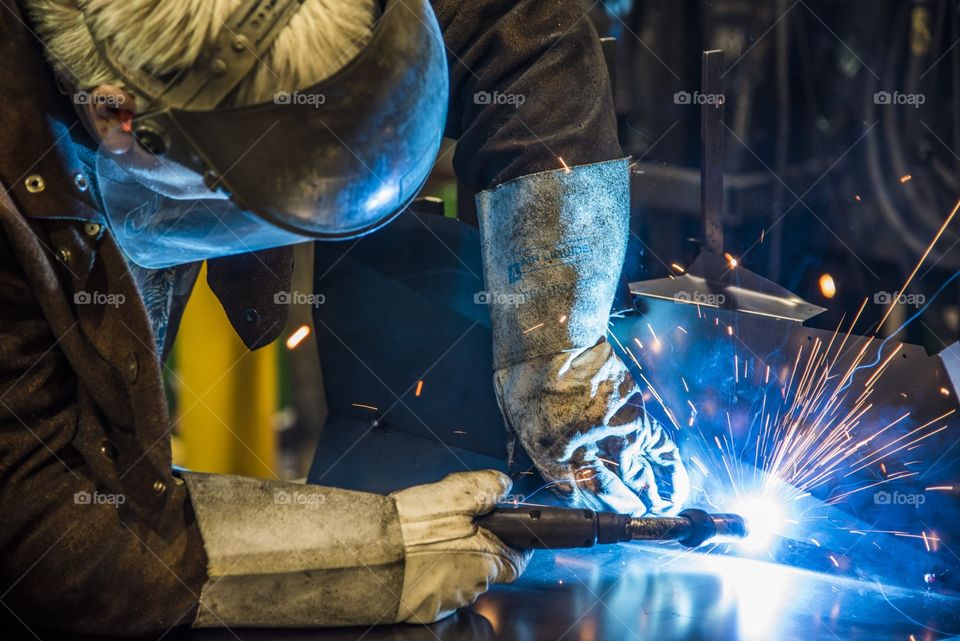 This welder is building a frame by welding bar steel together using fixtures to produce a ROPS frame for a heavy equipment Cab. 