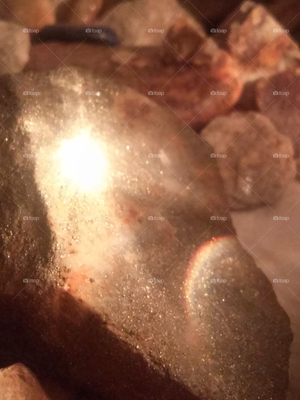 I Love Rocks!! Been Collecting 
Since I was 10 yrs. old . The Rocks, I found went into a Shoe box .  Now, they are in, Our  bedroom , over 10 fold, I am by the way 58 yrs. old. 
Now what i said, has led up to the 
Picture being seen.  One night before i retired to my bed, i noticed something quite neat .
I have a small desk lamp, without a shade, on my little table, next to my bed.  Then i have a folding table , where i have a typewriter, i plan on finally, typing my children's books, and life story, along with Rocks Galore all over, and Rock salt lamp.  I have a rock that just glistens .  Well, when the table lamp ( without the shade) + the Rock Salt Lamp + the glistening rock = That what is seen in this picture !!  Which to me, looks like , a glowing cross with an image on it' s left side and a Rainbow on the bottom left to middle. When i saw this, i quickly grabbed my phone and clicked to the camera icon.  To me, it sounds weird, to say i quickly grabbed my phone.  And for me i am talking weird, because i just got the phone i now have from my son, literally around this past Christmas. I have an Olympus camera i have been using for years. And i was using a little, tiny, LG Phone with no camera . I remember my Dad , Loved to take pictures, with His 35mm Kodak camera. And oh the slides and pictures He would take!! And when i got my first camera, Wow i was so excited!!  It had tiny little flash bulbs , a strap.  Then when i got older for my birthday i got my first Instamatic Camera by Kodak. So to this day, i am glad my dad instilled in me a great hobby, besides collecting Rocks.  I really do like Photography .  Because a picture really does say a thousand words.  And with having 6 children, 1 grand daughter so far, I am grateful for cameras, and the pictures that result from them.  What blessed beauty we have from an Almighty Maker above, who is the Greatest Artist, and provides us, His Children, from Designer Rocks to Pictures of really cool and neat Art.