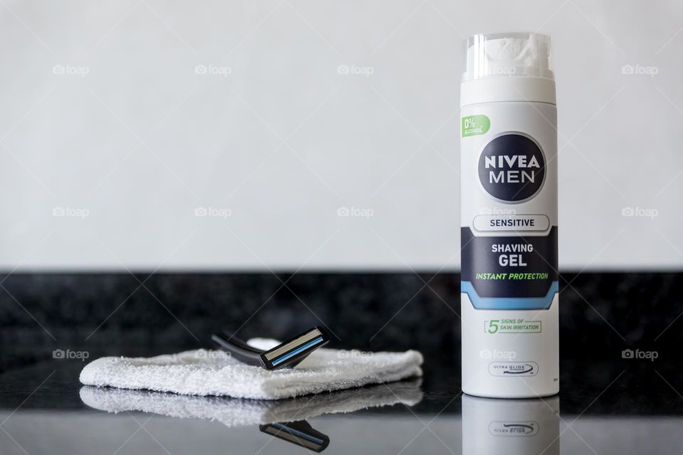 Nivea men sensitive shaving gel with razor on white towel on black grey granite 