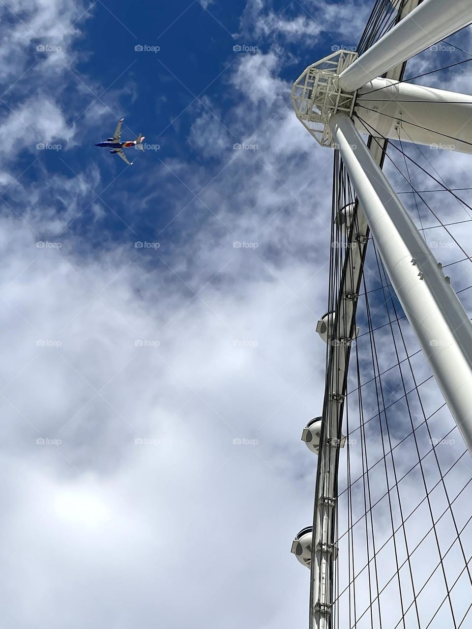 Plane flying near Ferris wheel