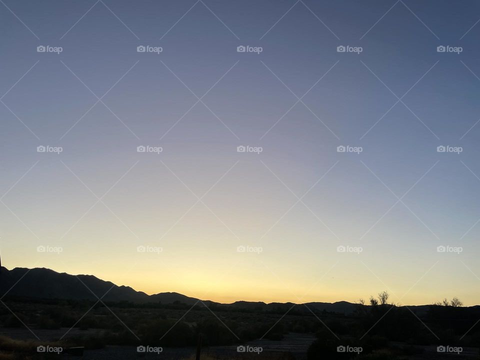 A bright yellow sunset with mountains.