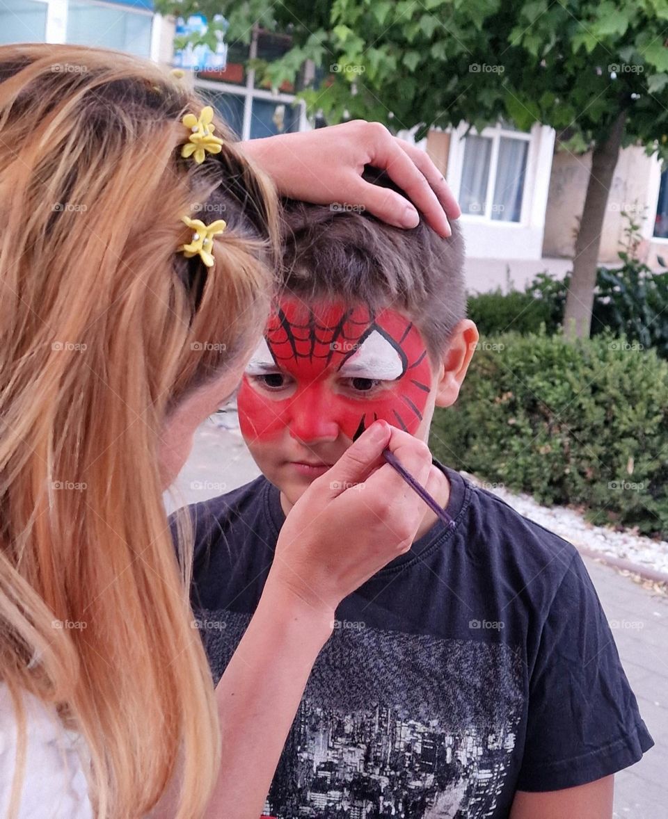 blonde girl painting a boy on her face