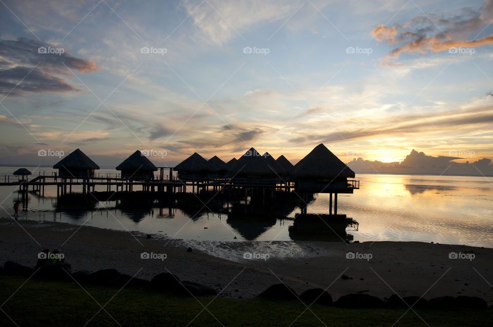 Vacationing tourist hold up in bungalows are front row to a Tahitian sunset both beautiful and serene as the sun descends into the pacific horizon.