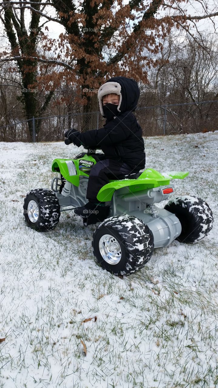 Child riding four wheeler in the snow