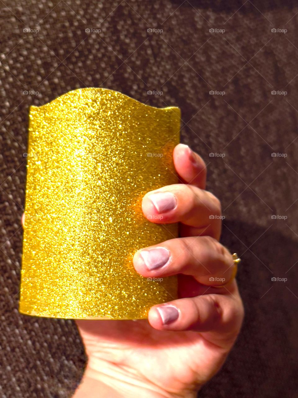 Holding a golden sparkling candle with one hand and manicured hands.