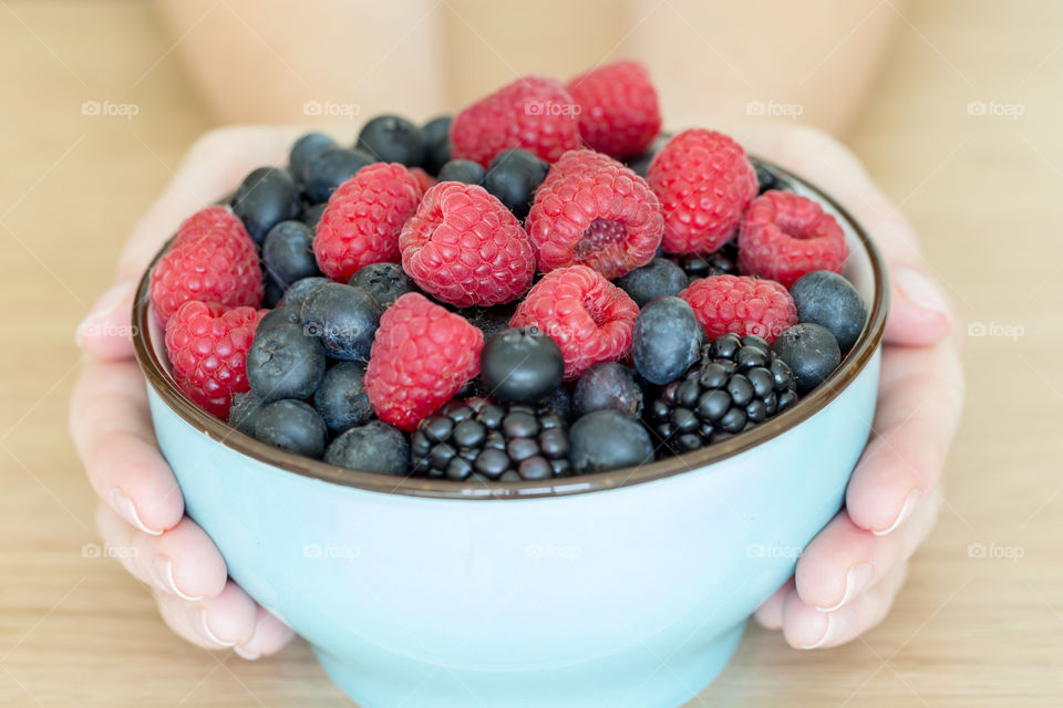 Bowl of fresh organic berries in hands as healthy breakfast option