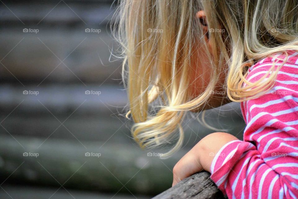 Girl standing on a wooden fence