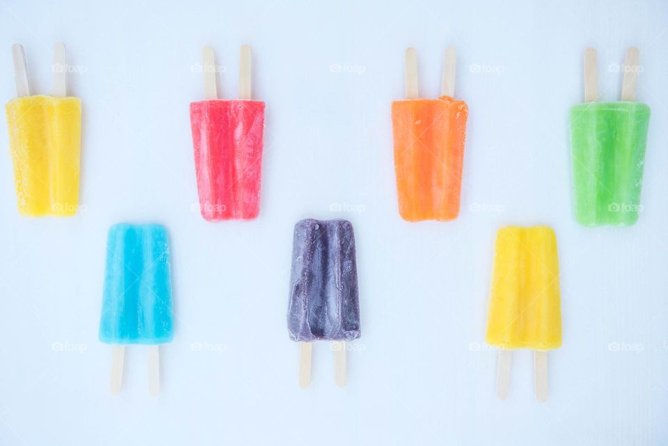 Flat lay of frosty frozen popsicles in an assortment of different colors 