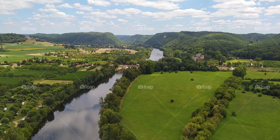 countryside landscape seen from above, a river, a meadow, fields and in the background green hills