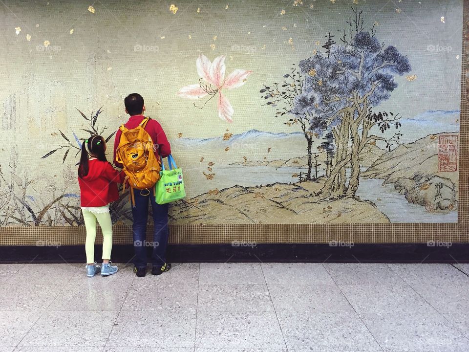 Father and daughter looking at a mosaic wall