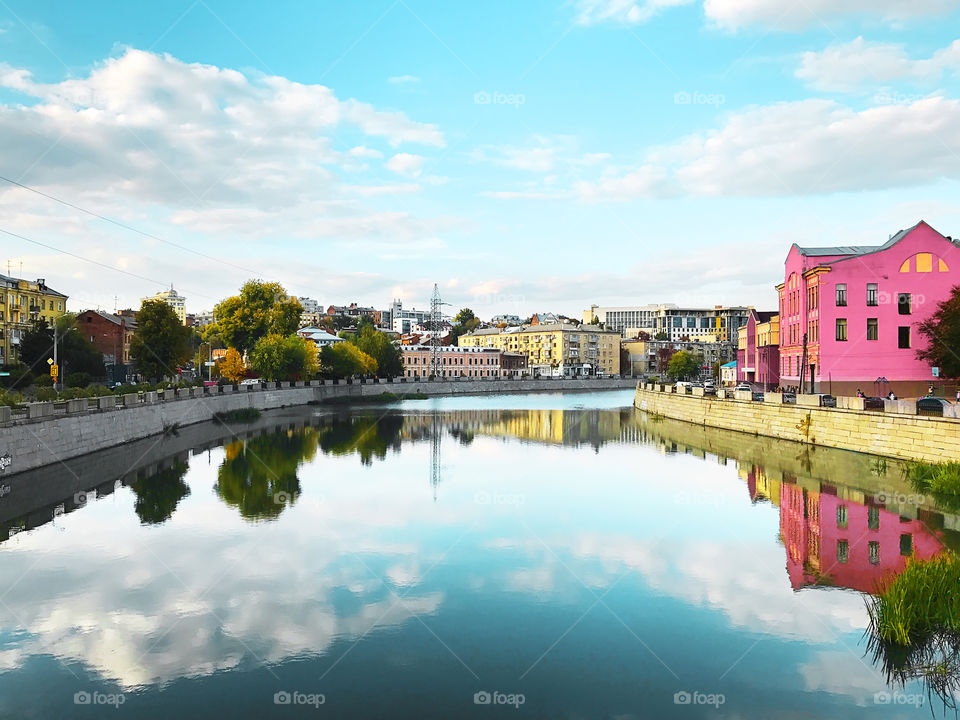 Reflection of a beautiful cloudy sky over old town in city river 