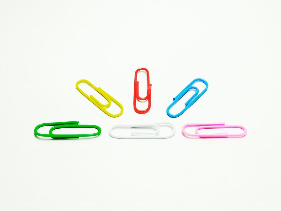 Multi colored paper clips against white background