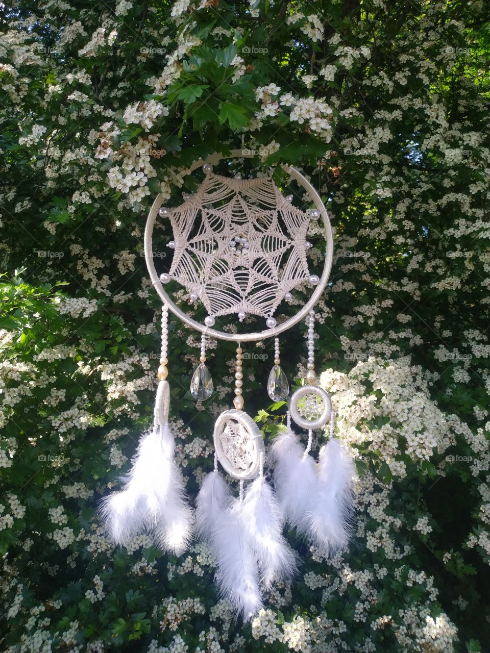 shamanic things white dreamcatcher with crystals on a background of a blossoming tree