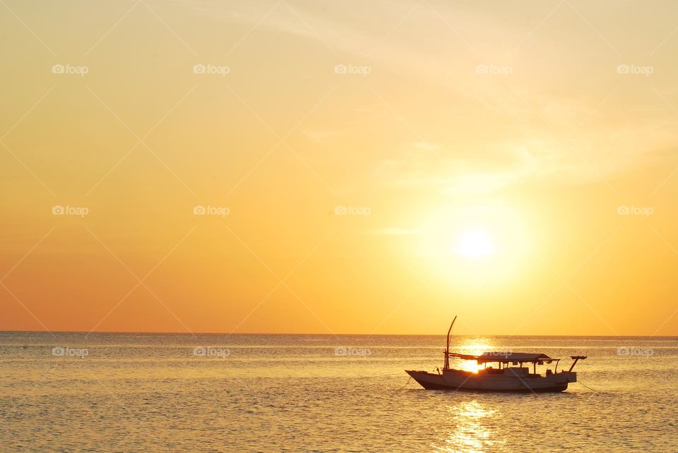 a ship in the middle of the sea at a yellow sunset