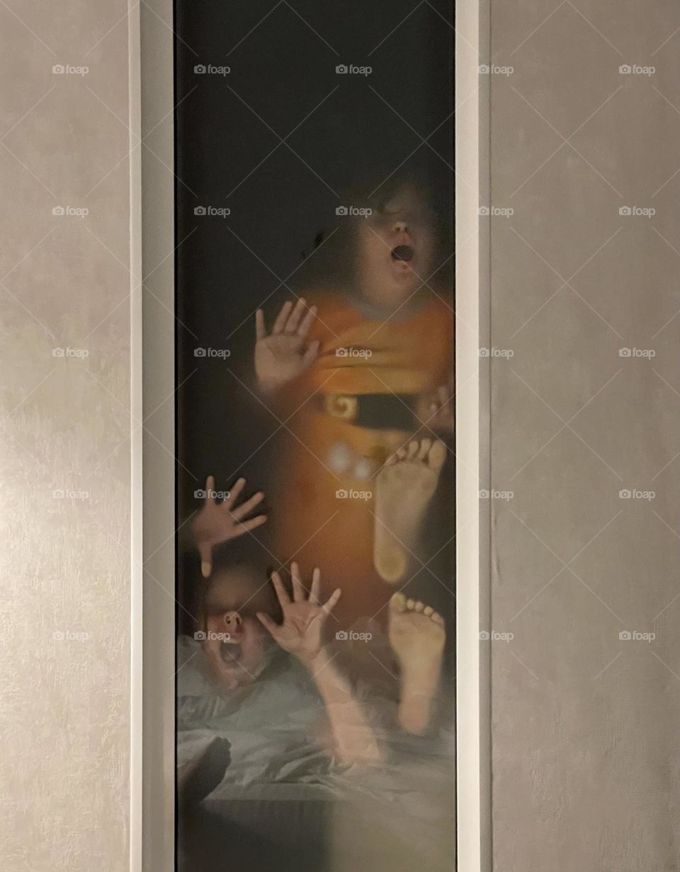 Children make faces, leaning against the window glass