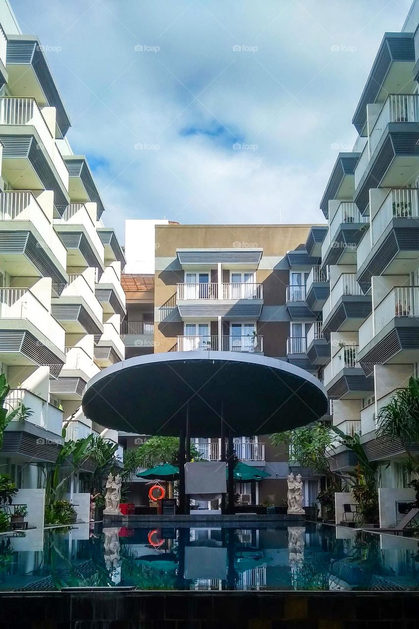 Gazebo by the swimming pool and surrounded by multi-storey hotels in low angle view