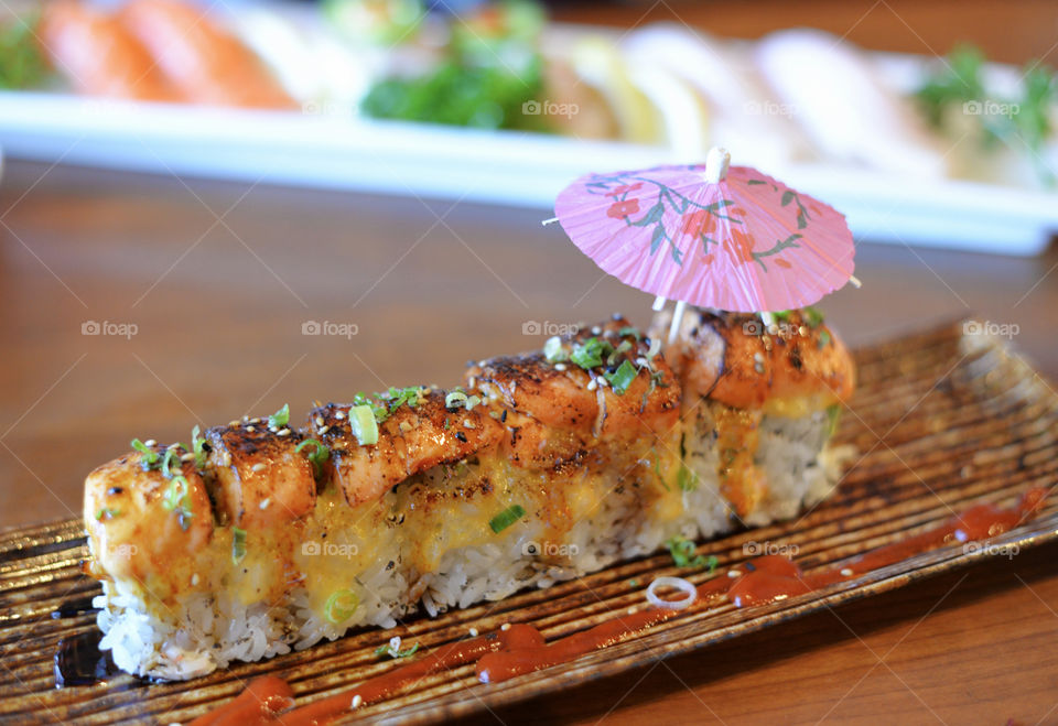  Tasty Baked salmon and rice roll on a platter with a mini umbrella 