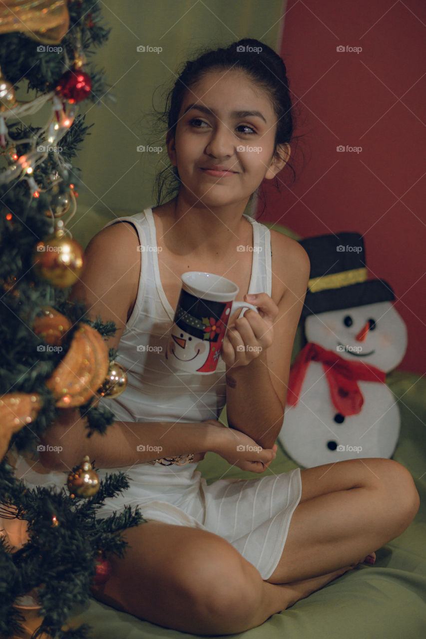 Girl enjoying a hot chocolate at Christmas, girl by a Christmas tree