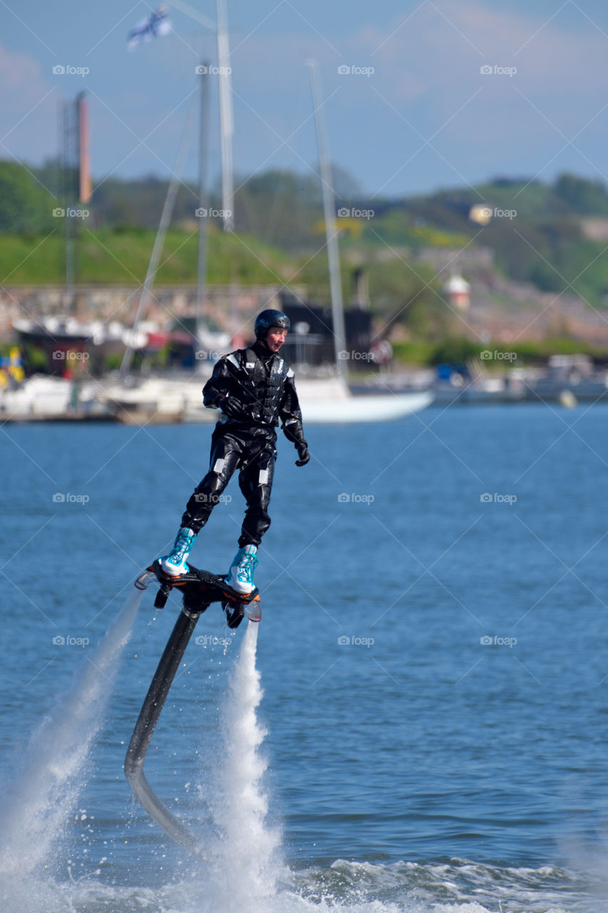 Helsinki, Finland - June 9, 2017: Unknown man performing hydroflight stunts with water jetback at the  Kaivopuisto Air Show with Suomenlinna fortress island on the background on sunny summer evening above the Baltic Sea in Helsinki, Finland.