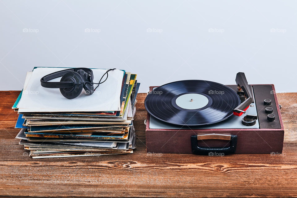 Stack of many black vinyl records, turntable vinyl player and headphones put on the stack. Classic stereo set. Candid people, real moments, authentic situations