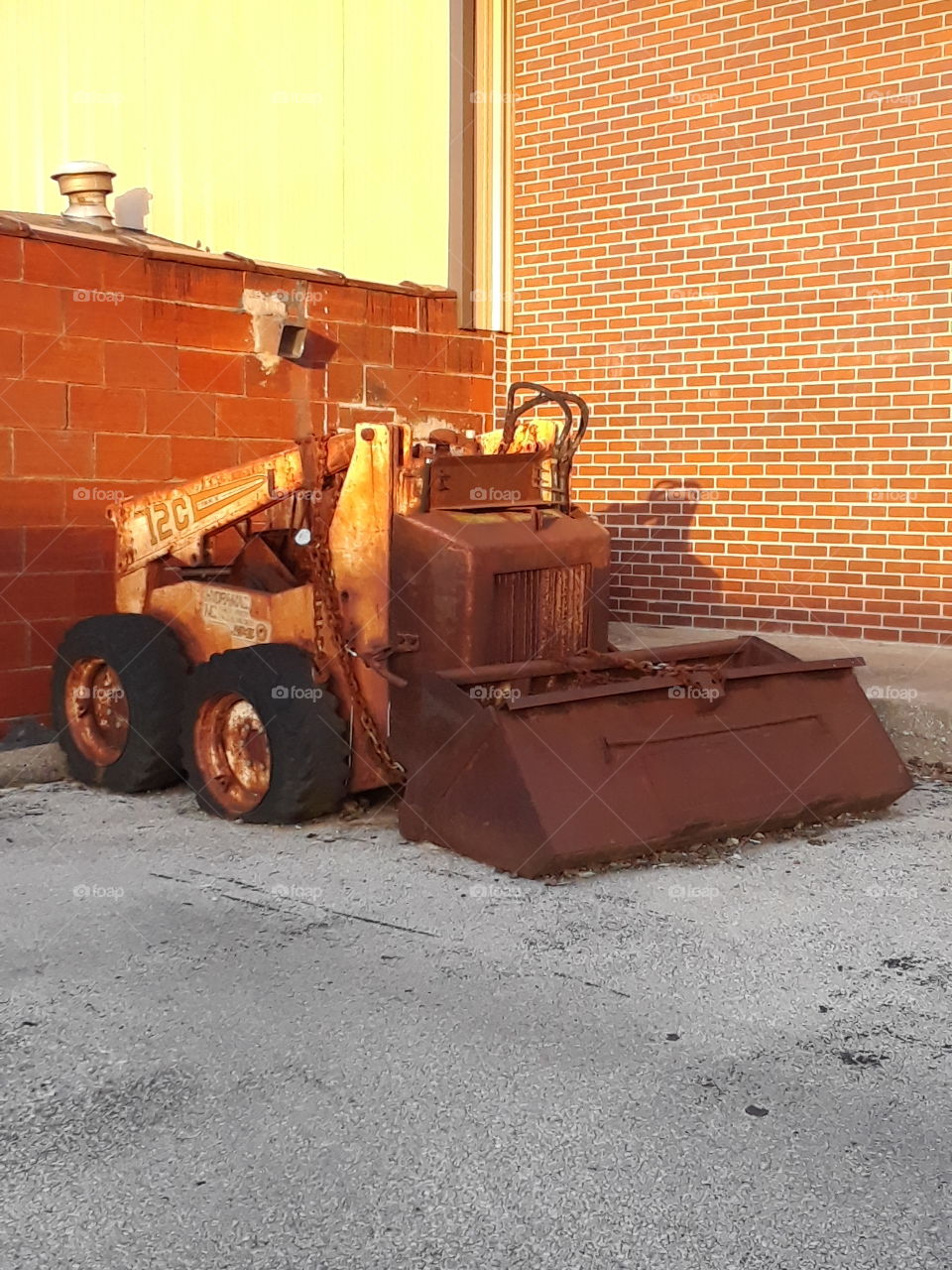 old tiny rusty  bulldozer with a brick wall