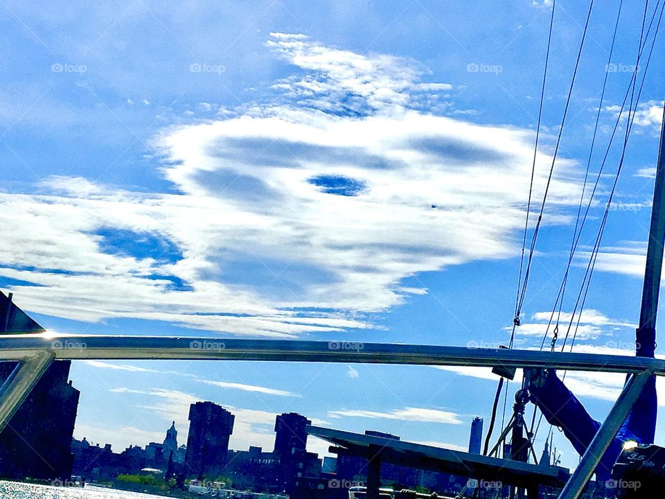 A most unusual photograph of a cloud pattern that appears to be in motion in the sky over Newtown Creek in Long Island City, Queens, NY. It looks as if zooming by at great speed. 2021. Hypnotic Productions
