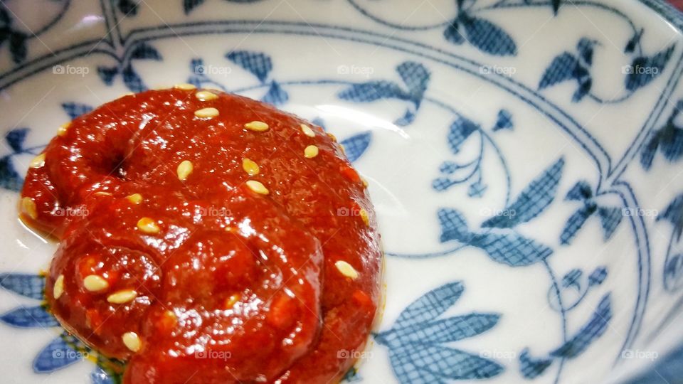 Gochujang - Korean spicy chilli paste in a small dish, covered with some sesame seeds.