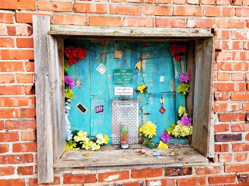 A framed window display allows locals to take or leave money or objects as their situation dictates